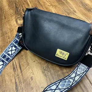 Casual black crescent shoulder bag for men and women, featuring a wide patterned strap.