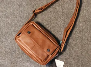 Men's casual brown leather crossbody shoulder bag detail view with front pocket and metal snaps.