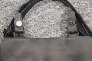Black leather messenger bag strap detail, sturdy metal hardware and magnetic snap closure.