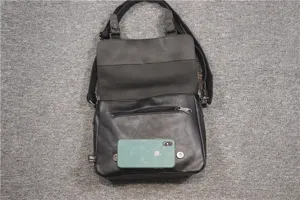 Detail view of black casual messenger bag showing size with phone, ideal for daily use.