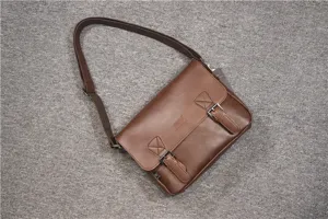 Brown synthetic leather messenger bag detail, vintage student satchel strap and buckle view.
