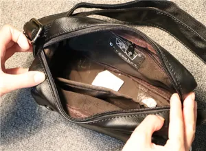 Detail view of the black men crossbody bag showing interior compartments and zipper lining.