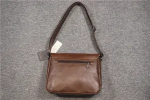 Close-up of brown leather casual messenger bag showing back zipper pocket and strap details.