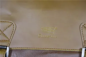 Close-up detail of the brown leather messenger bag showing embossed logo and texture.