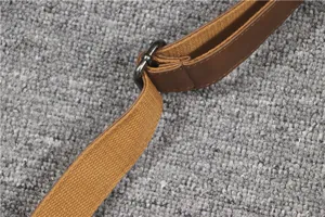 Strap detail of canvas shoulder bag showing adjustable metal buckle and leather trim.