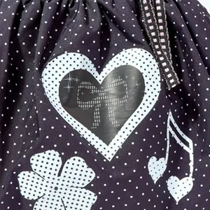 Detailopname van zwarte polkadot canvas tas met schattige hartstrik en muzieknoot print.