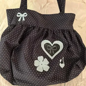 Gedetailleerd overzicht van zwarte stippen tote bag met schattige strik en hart print.