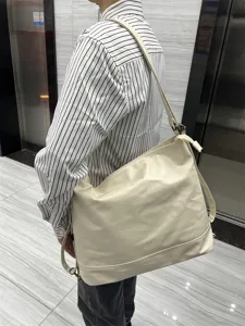 Vue détaillée d'un sac cabas souple blanc crème en cuir synthétique utilisé à l'épaule.