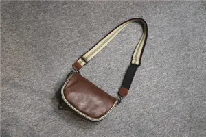 Close-up detail of the brown retro saddle bag showing textured leather and striped strap.