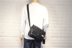 Black soft leather messenger bag detail, casual crossbody style with adjustable shoulder strap.