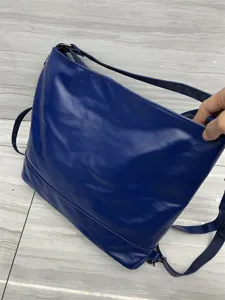 Détail du sac à dos convertible en cuir souple bleu montrant son grand espace et ses bretelles.