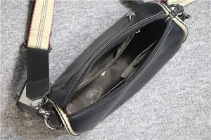 Black cylinder shoulder bag detail view showing interior compartments and wide strap.