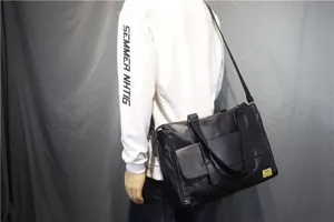 Detail shot of black PU leather mens messenger bag, showing shoulder strap and front flap pocket.