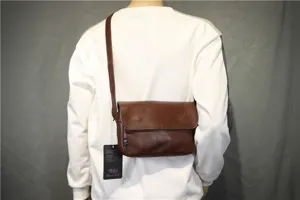 Detail shot of a brown leather messenger bag worn crossbody, showing design and texture.