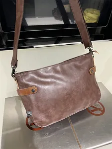 Vue détaillée du sac bandoulière rétro en cuir souple marron foncé pour homme avec boucles.