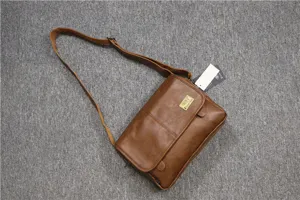 Brown leather messenger bag detail showing texture, flap closure, and adjustable shoulder strap.