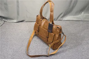 Detail view of brown PU leather business briefcase with dual handles and shoulder strap.