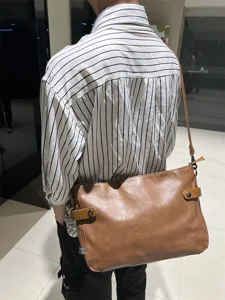 Vue détaillée du sac bandoulière marron en cuir pour homme, avec texture souple et sangle.