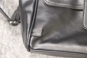 Detailed view of men's black leather business shoulder bag showing texture and brand tag.