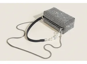 Close-up detail of luxury rhinestone evening bag with sparkling crystals, pearl accent, and chic chain strap.