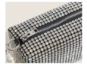 Close-up detail of luxury full rhinestone cylindrical evening bag, sparkly crystal texture.
