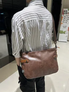 Vue détaillée du sac bandoulière pour homme en cuir souple marron porté au dos style.