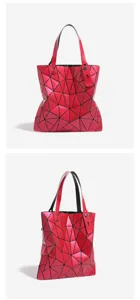 Vue rapprochée du sac cabas géométrique rouge montrant des panneaux triangulaires et des poignées.