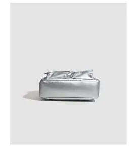 Detailed view of the silver metallic shoulder bag with cute front pockets and bow accents.