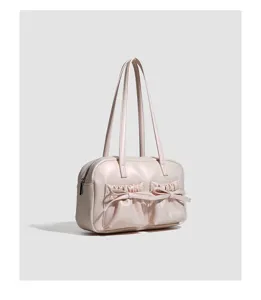 Detailed view of the pink shoulder bag featuring cute bow-knotted front pockets and straps.