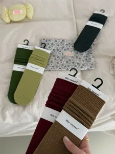 Gedetailleerd overzicht van geribbelde damessokken in herfstkleuren met merkimpakking.
