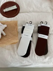 Gedetailleerd overzicht van geribbelde sokken in neutrale kleuren met papieren verpakking.