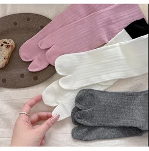 Close-up detail shot of soft cotton split-toe socks in pink, white, and grey colors.