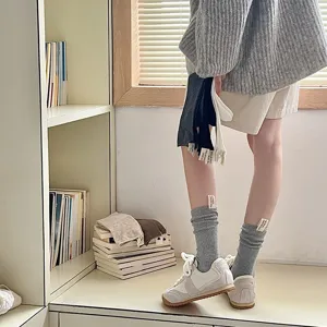 Detailansicht dicker Strick-Socken mit kleinen Stoffetiketten für Damen, ideal für den Winter.