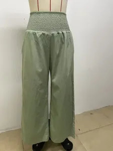 Close-up detail of the light green loose wide-leg casual trousers with high smocked waist.