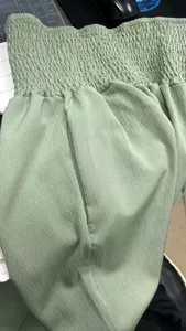 Light green casual trousers detail, high smocked waist design, soft textured fabric.