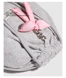 Gros plan detail de sac à dos cordon gris avec un nœud rose et des pièces en métal.
