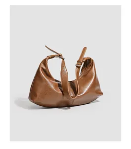 Braune Leder-Baguette-Tasche Detailansicht mit glatter Textur und verstellbarem Gurt.