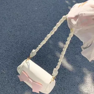 Sweet white cylindrical crossbody bag with a pink bow and braided strap for daily casual style.