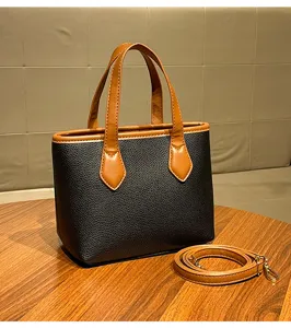 Details showing the texture and handle craftsmanship of the black and brown bucket handbag.