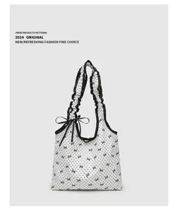Detailed view of white polka dot canvas tote bag, featuring ruffled shoulder strap and bow.