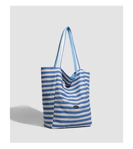 Close-up detail of the blue and white striped canvas tote bag, showing strap texture and badge.