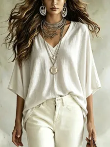 Close-up detail of women's autumn V-neck loose linen casual blouse with layered necklaces.