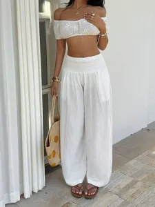 Detailed view of white resort style loose wide-leg trousers and matching crop top outfit.
