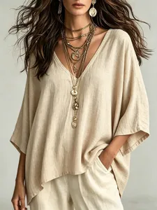 Close-up detail view of casual V-neck linen blouse paired with stylish layered gold jewelry.
