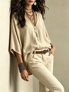 Detail view of a casual V-neck linen top, paired with stylish layered necklaces and belt.