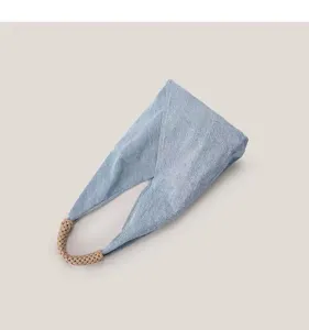 Gros plan détaillé du sac à main bandoulière en tissu denim bleu clair avec poignée tressée.
