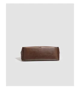 Close up of brown soft leather tote bag bottom, showing detailed stitching and fine texture.