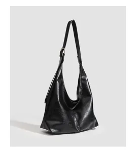 Close-up of black soft leather shoulder bag, showing adjustable strap and slouchy design.