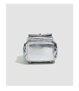 Silver quilted backpack bottom detail, metallic shiny texture with protective feet.