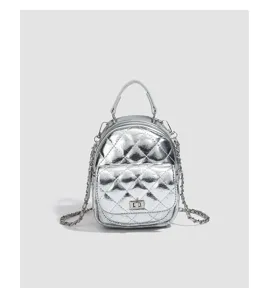 Silver metallic quilted mini backpack detail, featuring stylish chain straps and chic metal lock.
